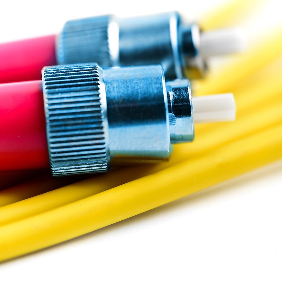 Los dos extremos del conector de empalme de un cable óptico sobre algún otro cable amarillo