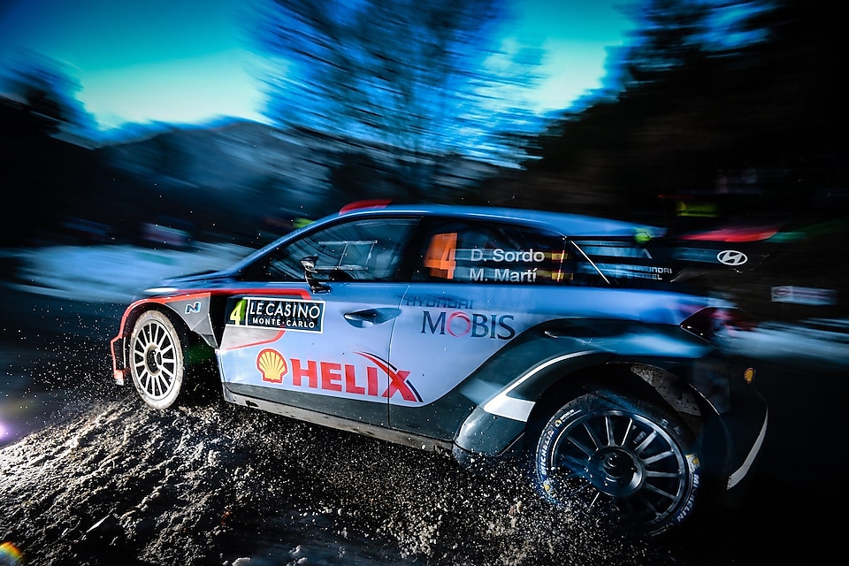 Coche de rally corriendo a gran velocidad al amanecer en el Campeonato del Mundo de Rallyes