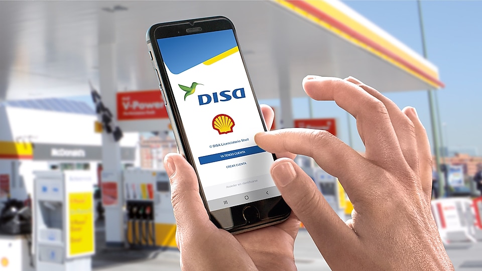 Smartphone mostrando la Nueva app Mi Energía DISA con estación Shell de fondo