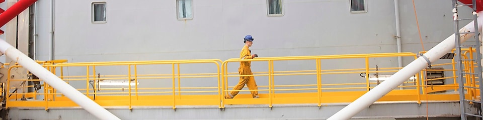 Ingeniero caminando por una plataforma en alta mar en el Mar del Norte en Aberdeen
