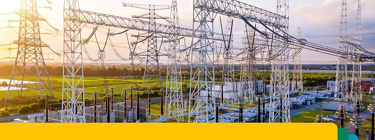 Transformatorstation met onderling verbonden hoogspanningsleidingen en apparatuur bij zonsondergang.