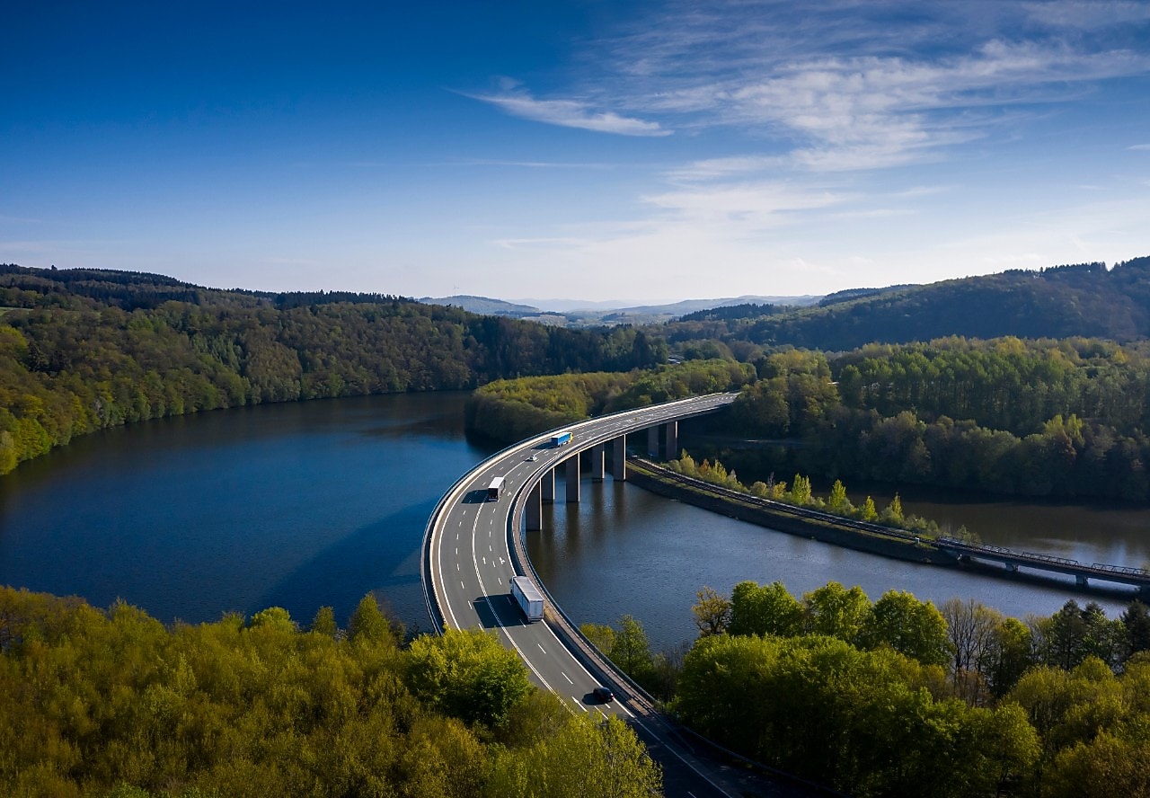 Camiones en un puente sobre un río y un bosque