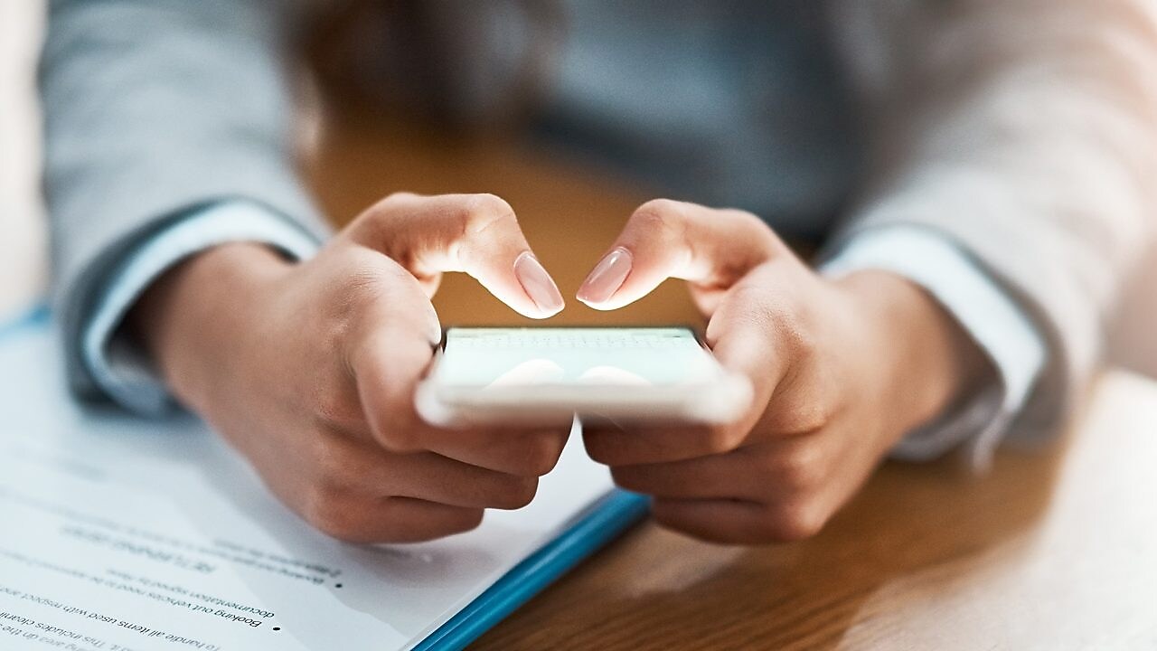 Two hands shown using a mobile device to send an email