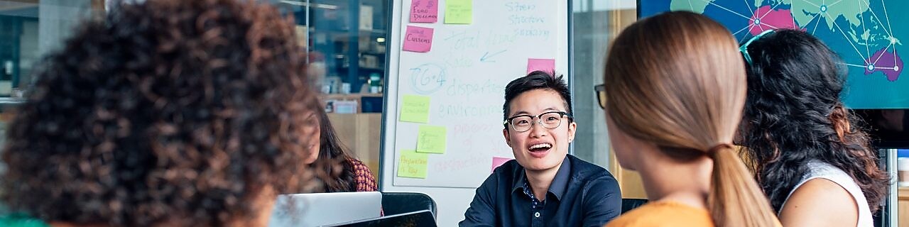  Cuatro hombres de negocios sentados alrededor de una mesa redonda leyendo documentos, alfombra gris y amarilla