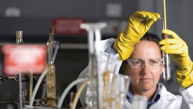 Mujer con gafas de seguridad llevando a cabo un experimento de laboratorio