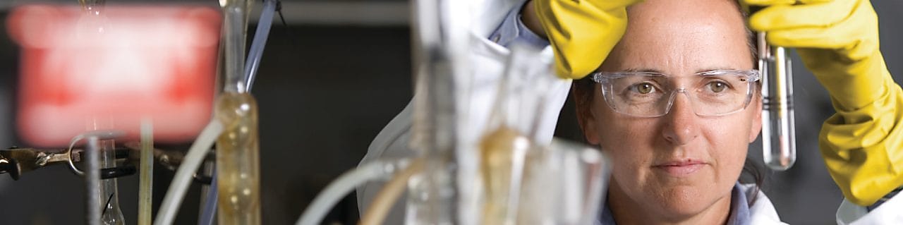 Mujer con gafas de seguridad llevando a cabo un experimento de laboratorio