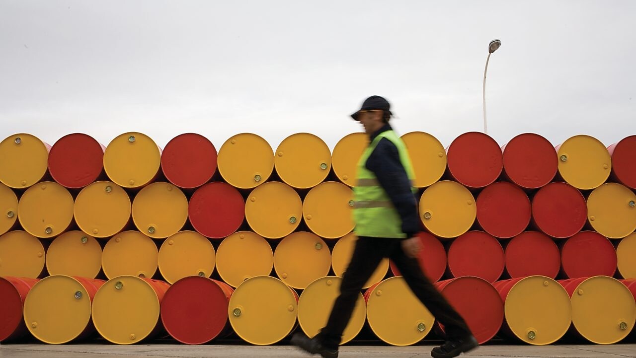 hombre pasa junto a barriles de lubricantes