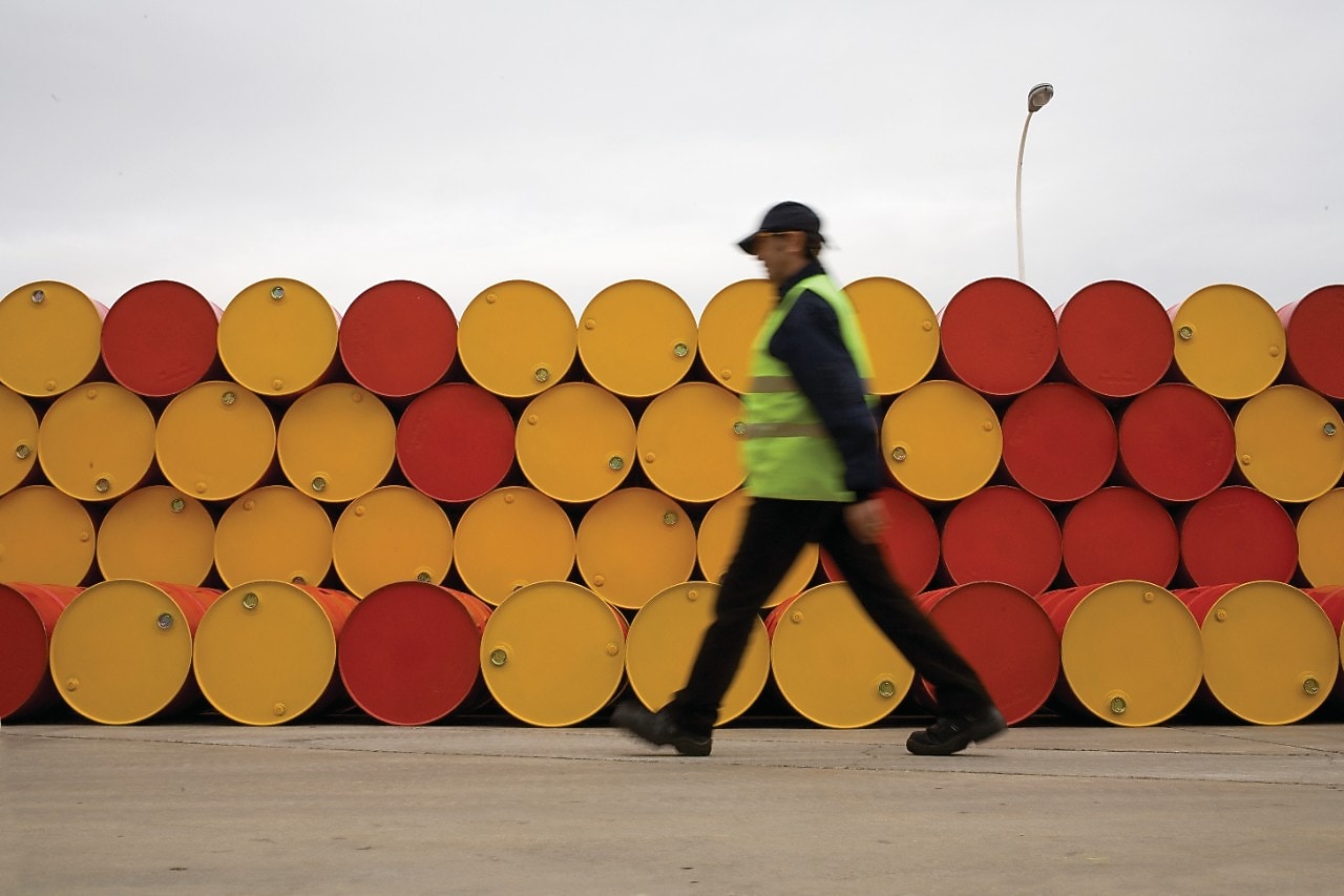 hombre pasa junto a barriles de lubricantes