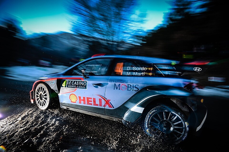 Coche de rally corriendo a gran velocidad al amanecer en el Campeonato del Mundo de Rallyes
