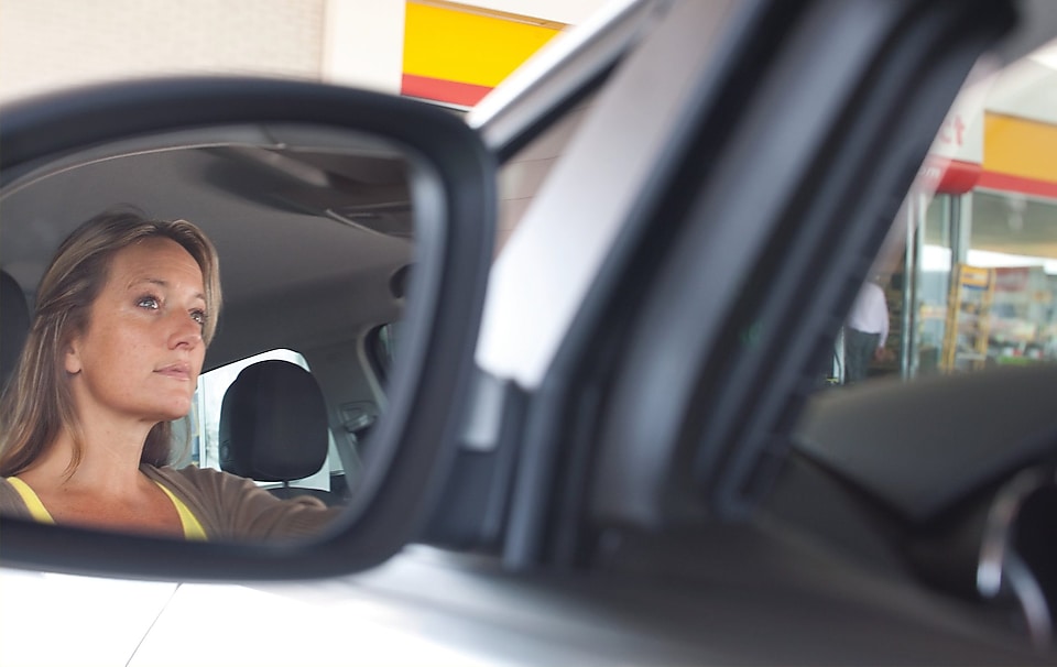 mujer conduciendo y su reflejo en el retrovisor derecho