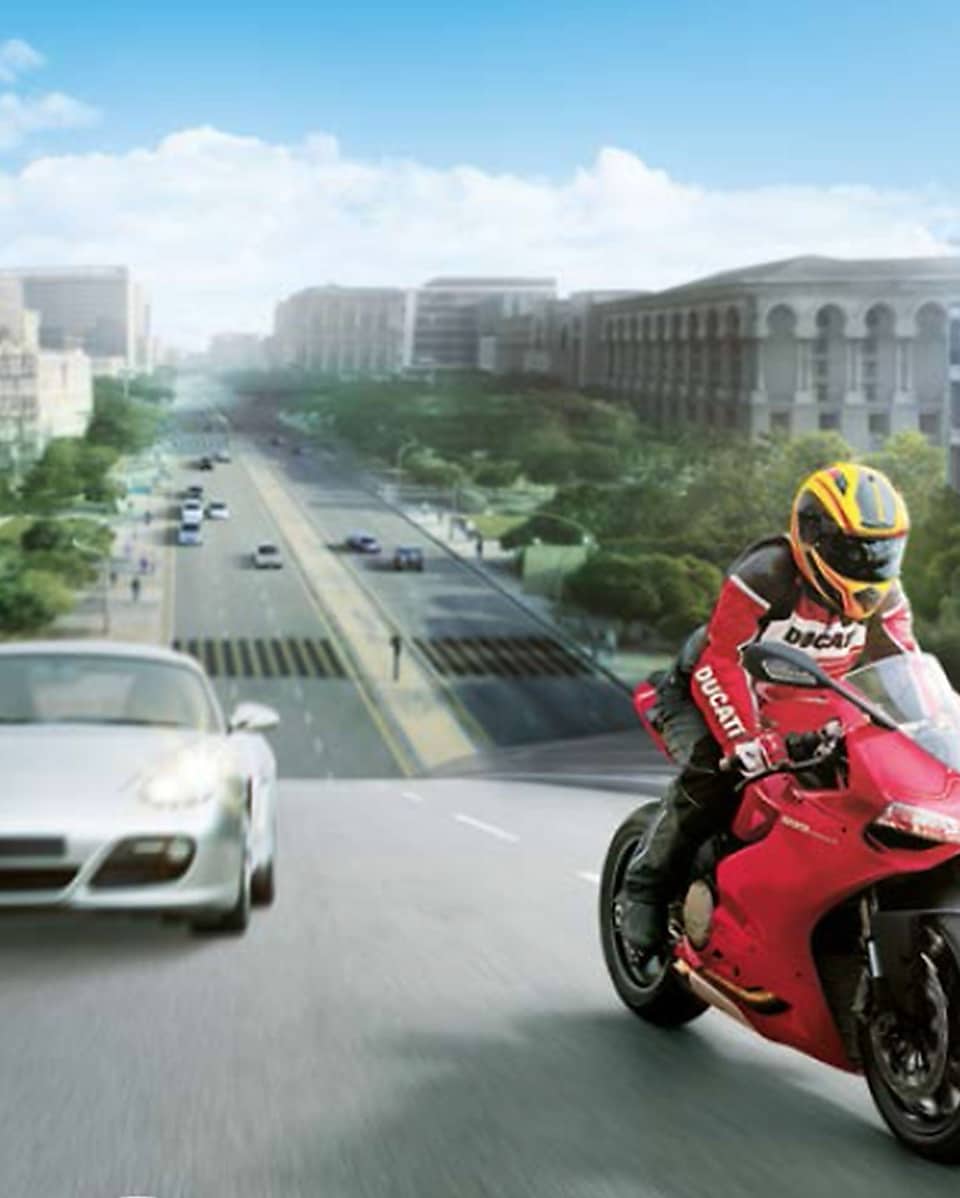 Motocicleta roja y piloto con coches y edificios al fondo