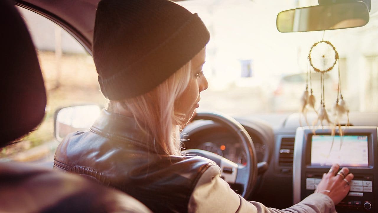 Una joven consulta las instrucciones mostradas en la pantalla de navegación integrada en su coche
