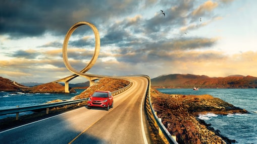 Coche rojo circulando por la carretera junto al río