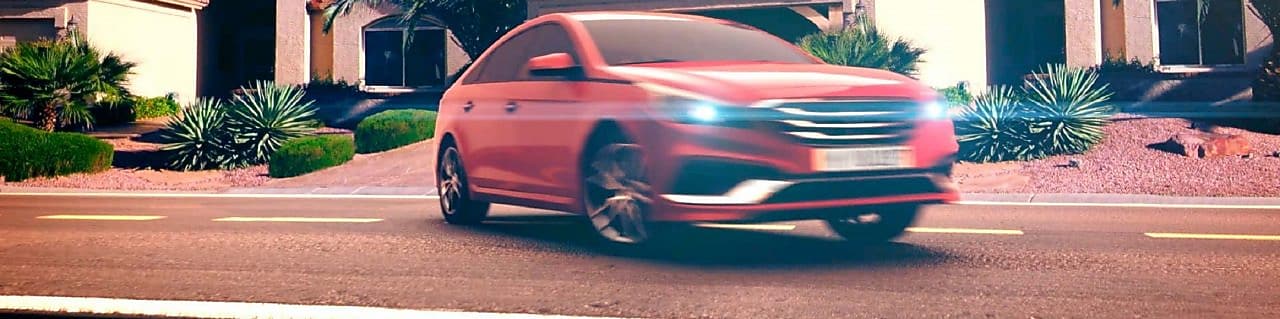 Coche rojo estacionado en el exterior de una casa con los faros encendidos al atardecer