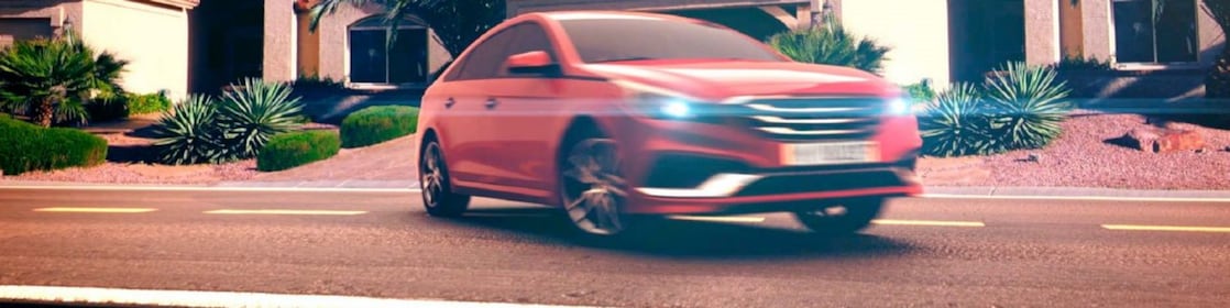 Coche rojo estacionado en el exterior de una casa con los faros encendidos al atardecer