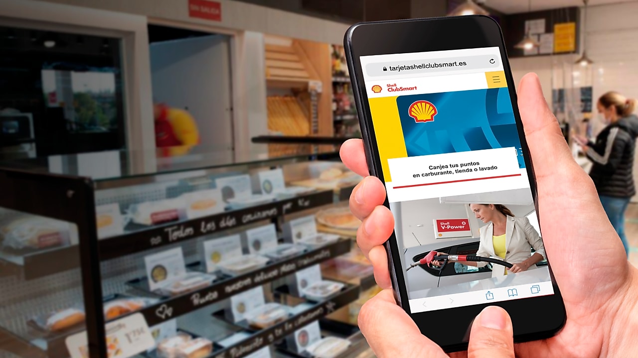 Mano con movil dentro de una tienda Shell