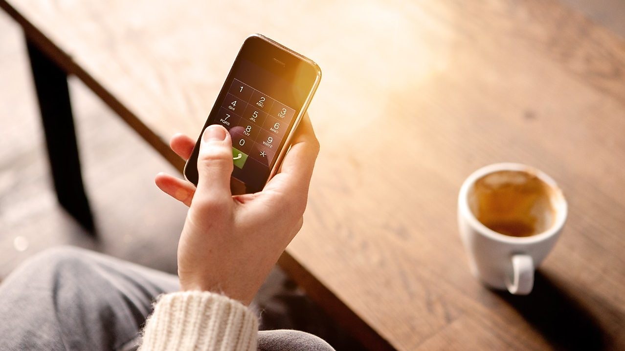 Imagen de teléfono móvil junto a taza de café